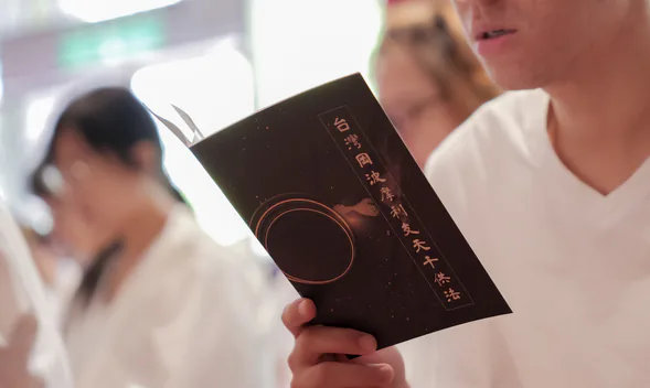 與會者手持法會手冊閱讀